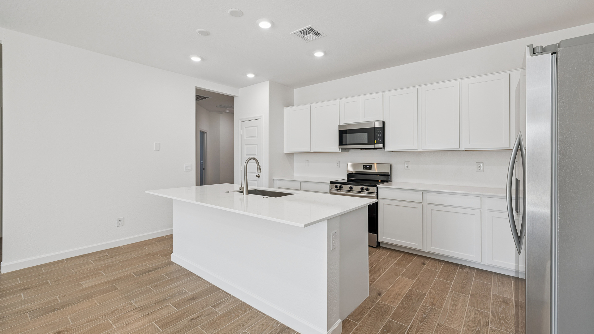 Bright and spacious kitchen with countertops, stainless steel appliances, and an island with bar seating.