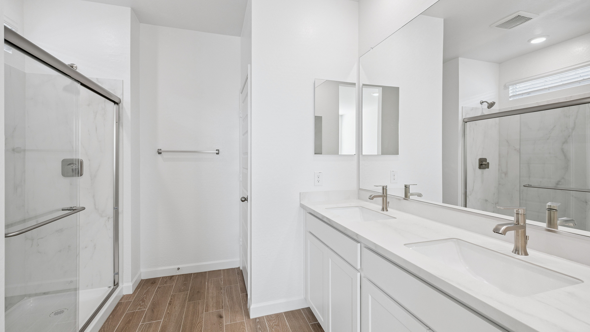 Modern primary bathroom with double vanities, countertops with a walk-in shower and a walk-in closet.