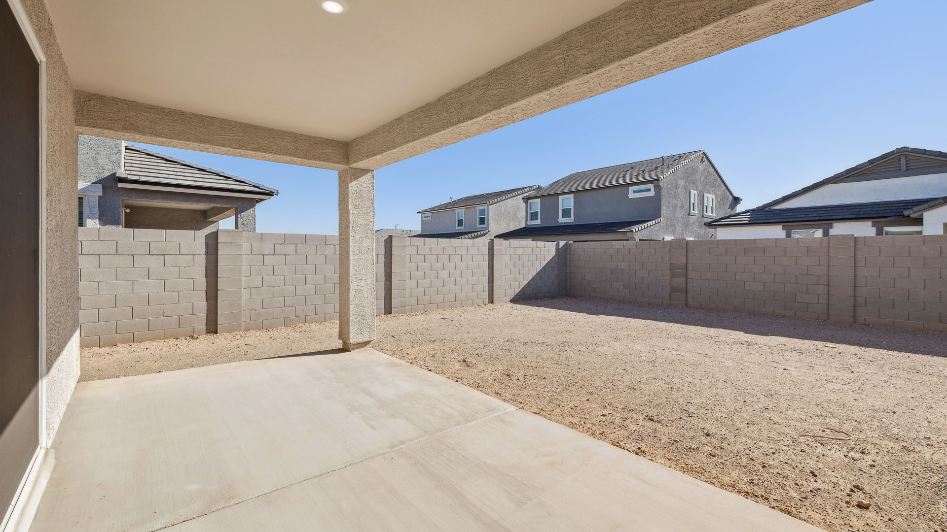 Outdoor covered patio with seating area overlooking a well-maintained lawn, perfect for relaxation.