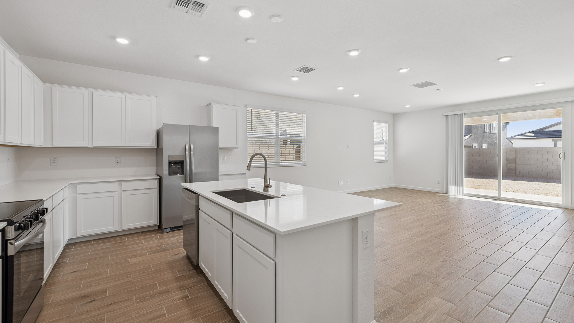 Bright and spacious kitchen with countertops, stainless steel appliances, and an island with bar seating.