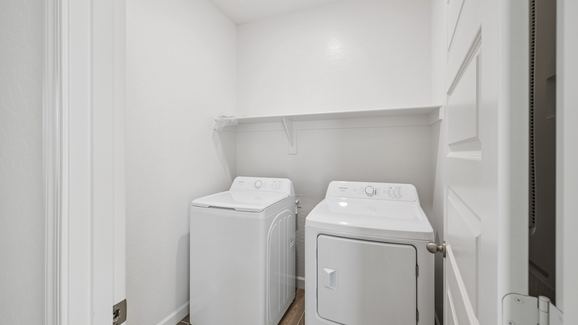 Spacious laundry room with washer and dryer connections and shelving for storage.