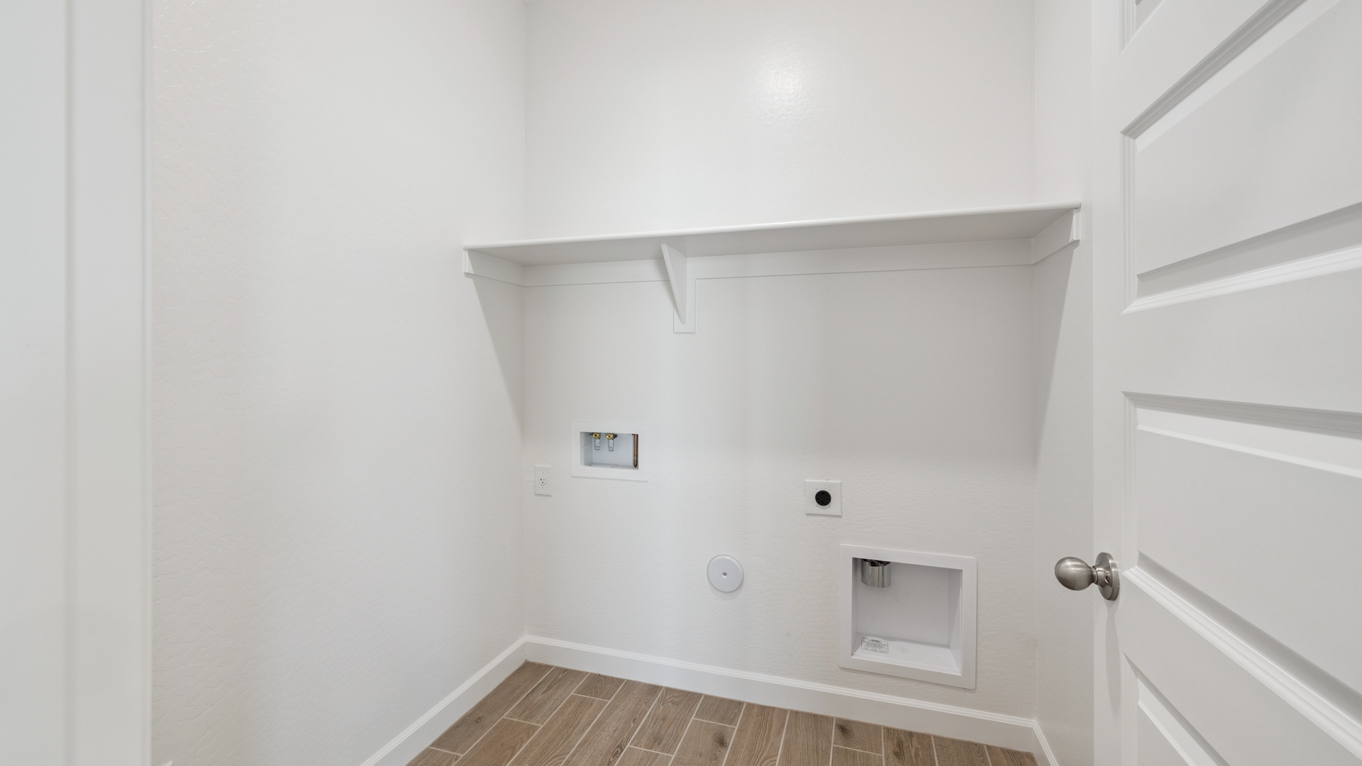 Laundry room with shelving for storage.
