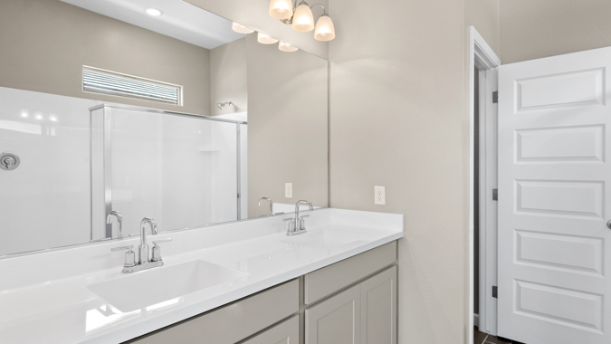 Primary bathroom with dual vanities and a walk-in shower.