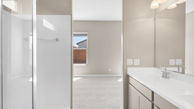 Primary bathroom with dual vanities and a walk-in shower.