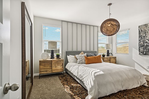 Bedroom featuring a bed with white bedding, two nightstands, and large windows.