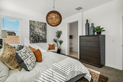 Bedroom featuring a bed with white bedding, a dresser, and large windows.