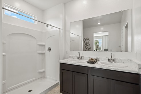 Bathroom with dual sinks and a walk in shower.
