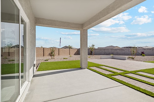 Covered patio and grass in backyard.