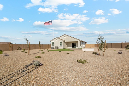 Rock and grass in backyard with covered patio.