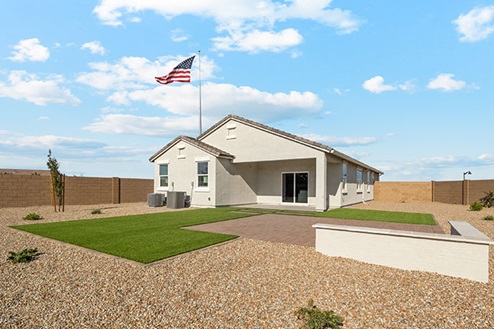 Rock and grass in backyard with covered patio.