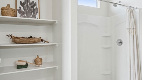 Modern primary bathroom with double vanities, porcelain countertops with a walk-in shower and a walk-in closet.