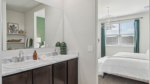 Modern primary bathroom with double vanities, porcelain countertops with a walk-in shower and a walk-in closet.