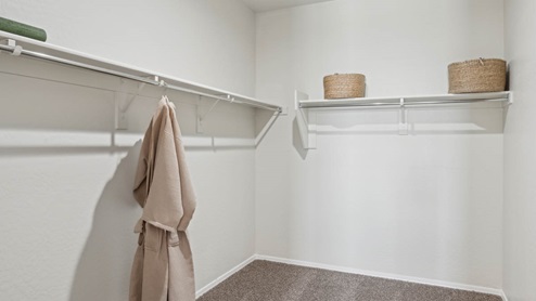 Modern primary bathroom with double vanities, porcelain countertops with a walk-in shower and a walk-in closet.