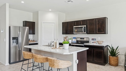 Bright and spacious kitchen with porcelain countertops, stainless steel appliances, and an island with bar seating.