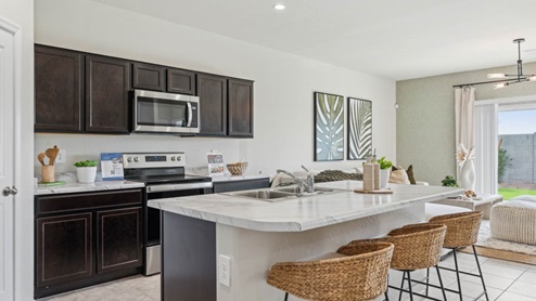 Bright and spacious kitchen with porcelain countertops, stainless steel appliances, and an island with bar seating.