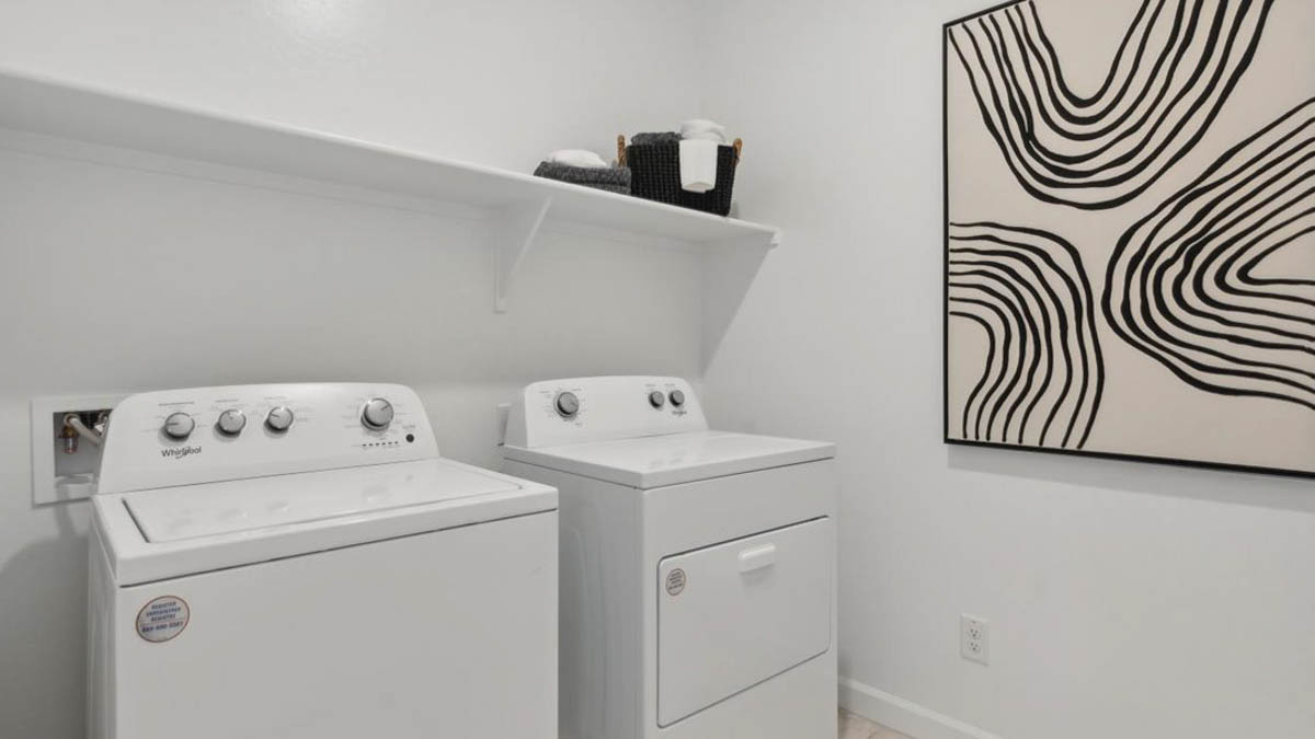 Spacious laundry room with washer and dryer connections and shelving for storage.