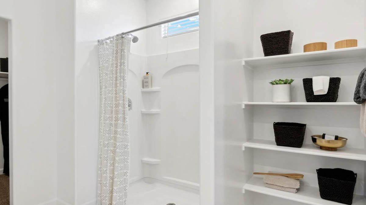 Modern primary bathroom with double vanities, porcelain countertops with a walk-in shower and a walk-in closet.