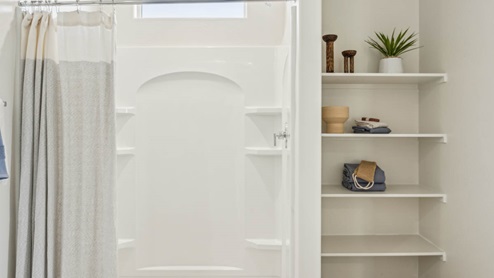 Modern primary bathroom with double vanities, granite countertops with a walk-in shower and a walk-in closet.