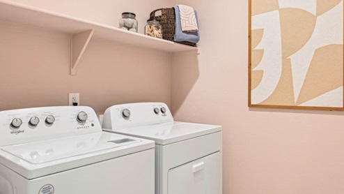 Spacious laundry room with washer and dryer connections and shelving for storage.