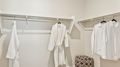 Modern primary bathroom with double vanities, granite countertops with a walk-in shower and a walk-in closet.