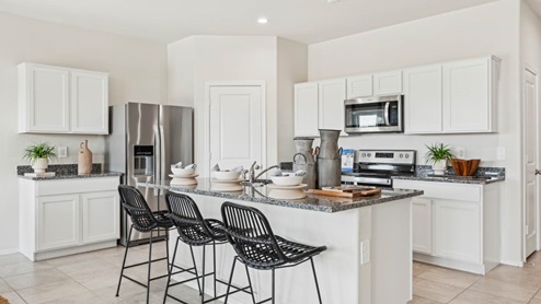 Bright and spacious kitchen with granite countertops, stainless steel appliances, and an island with bar seating.