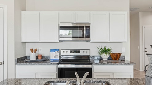 Bright and spacious kitchen with granite countertops, stainless steel appliances, and an island with bar seating.