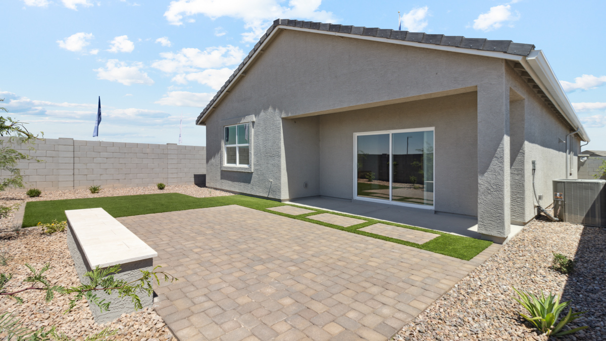 Exterior backyard view highlighting covered patio and paved seating area