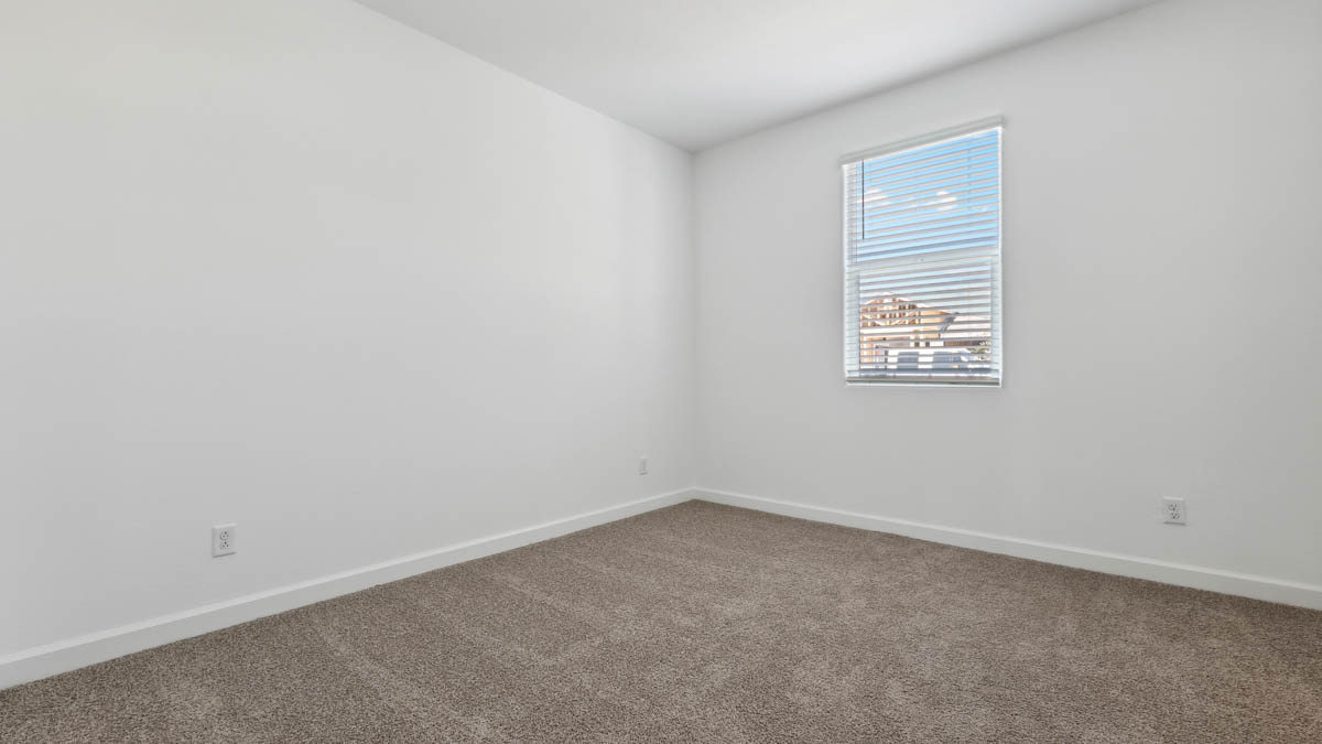bedroom with beige carpet, white walls and a window