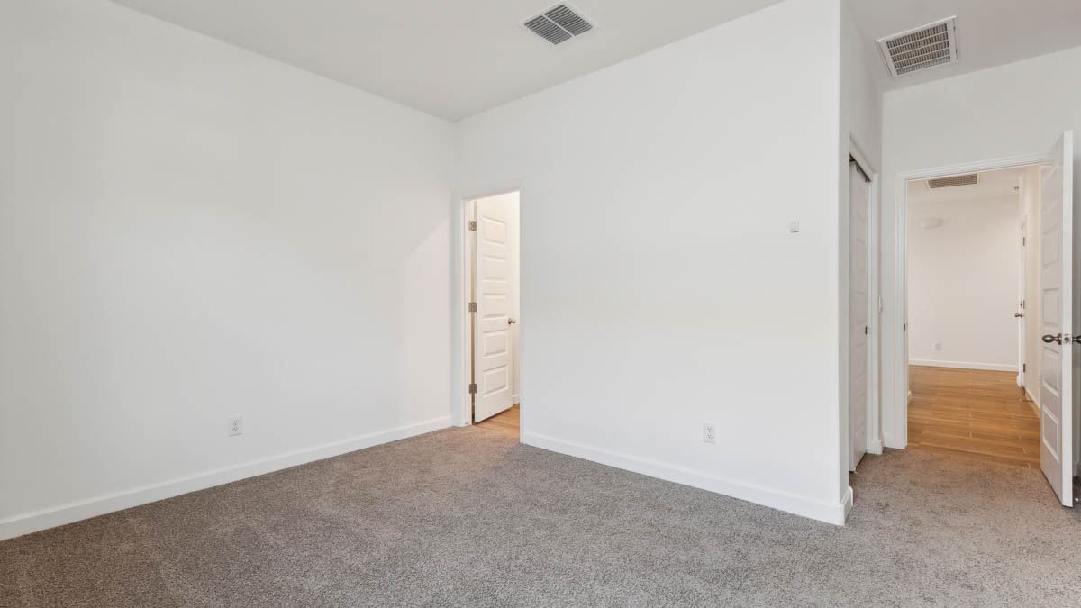bedroom with beige carpet, white walls and a window