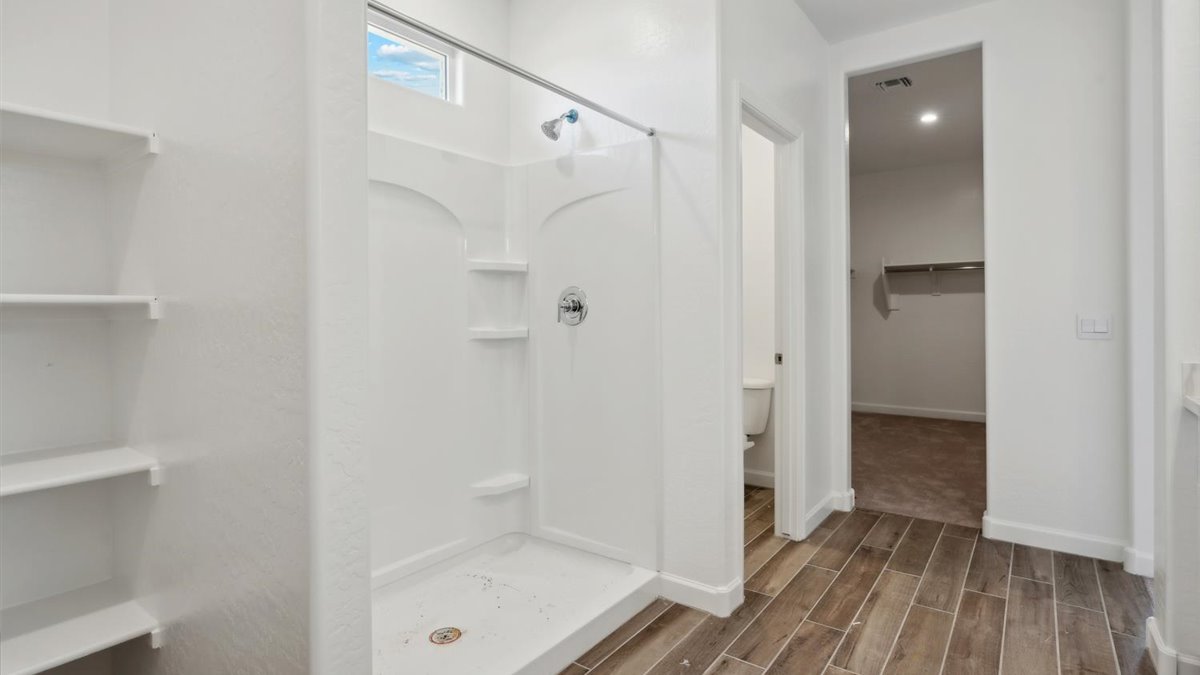 bathroom with dual vanity sinks, toilet, and a walk in shower