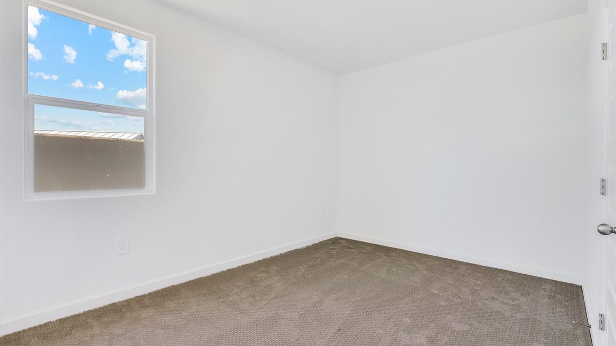 bedroom with beige carpet, white walls and a window