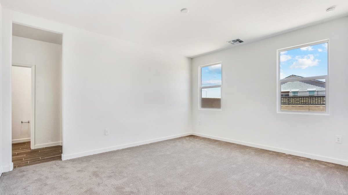 bedroom with beige carpet, white walls and a window