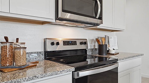 Bright and spacious kitchen with granite countertops, stainless steel appliances, and an island with bar seating.