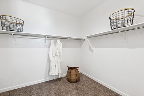 Modern primary bathroom with double vanities, with a walk-in shower and a walk-in closet.