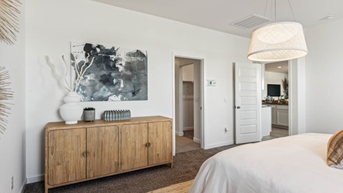 Primary bedroom with elegant light fixture, plush carpeting, and entryway to primary bath
