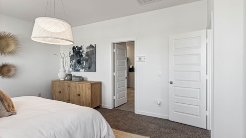 Primary bedroom with elegant light fixture, plush carpeting, and entryway to primary bath