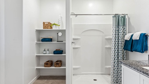 Modern primary bathroom with double vanities, granite countertops with a walk-in shower and a walk-in closet.
