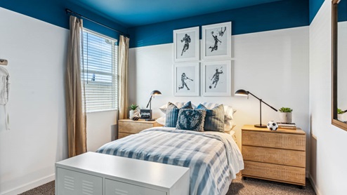 A vibrant kids' bedroom showcasing a neatly made bed, a stylish dresser, and a playful painting that adds charm.