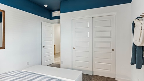 A vibrant kids' bedroom showcasing a neatly made bed, a stylish dresser, and a playful painting that adds charm.