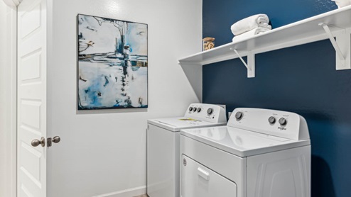 A laundry room featuring a washer and dryer, neatly arranged with ample space for laundry tasks and storage.