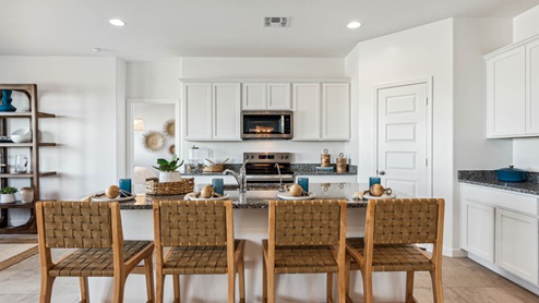Bright and spacious kitchen with porcelain countertops, stainless steel appliances, and an island with bar seating.