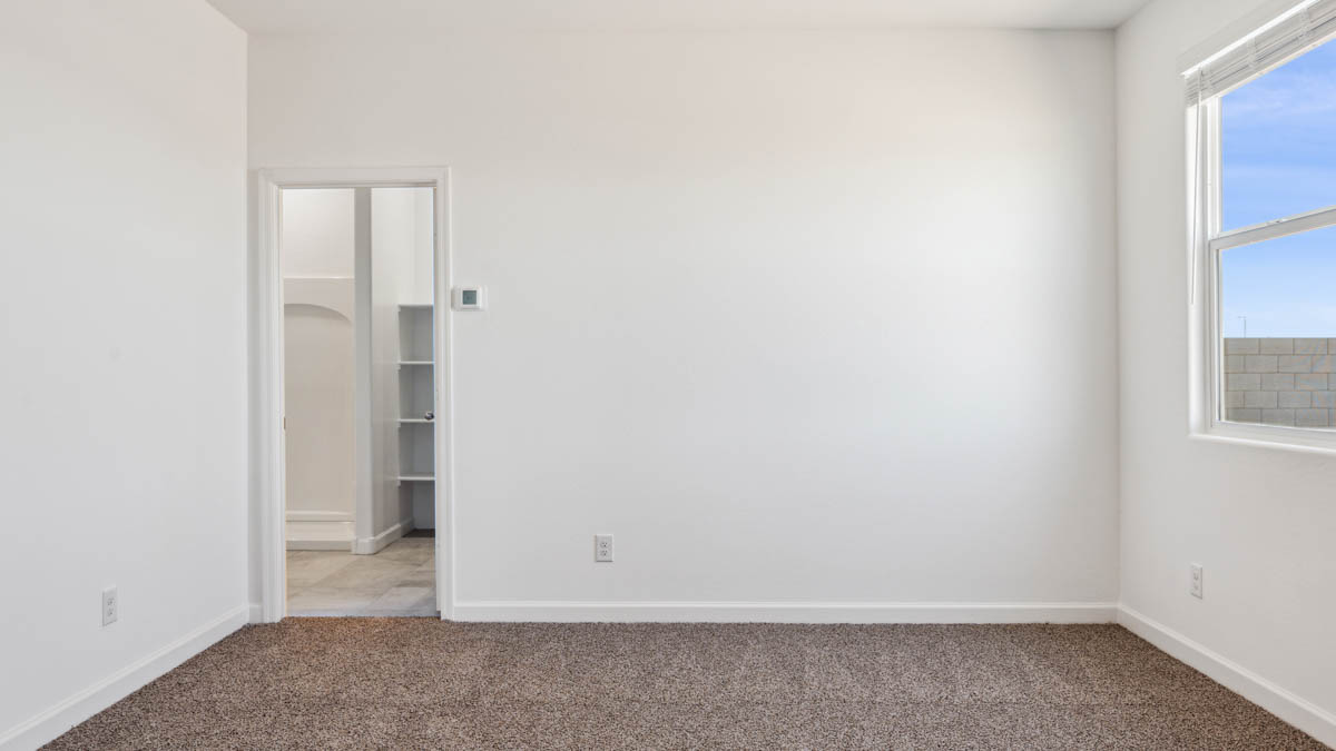 bedroom with beige carpet, white walls and a window