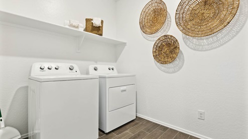 Spacious laundry room with washer and dryer connections and shelving for storage.