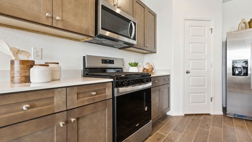 Bright and spacious kitchen with countertops, stainless steel appliances, and an island with bar seating.