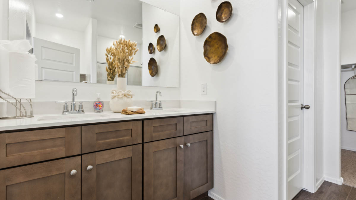 Modern primary bathroom with double vanities, with a walk-in shower and a walk-in closet.