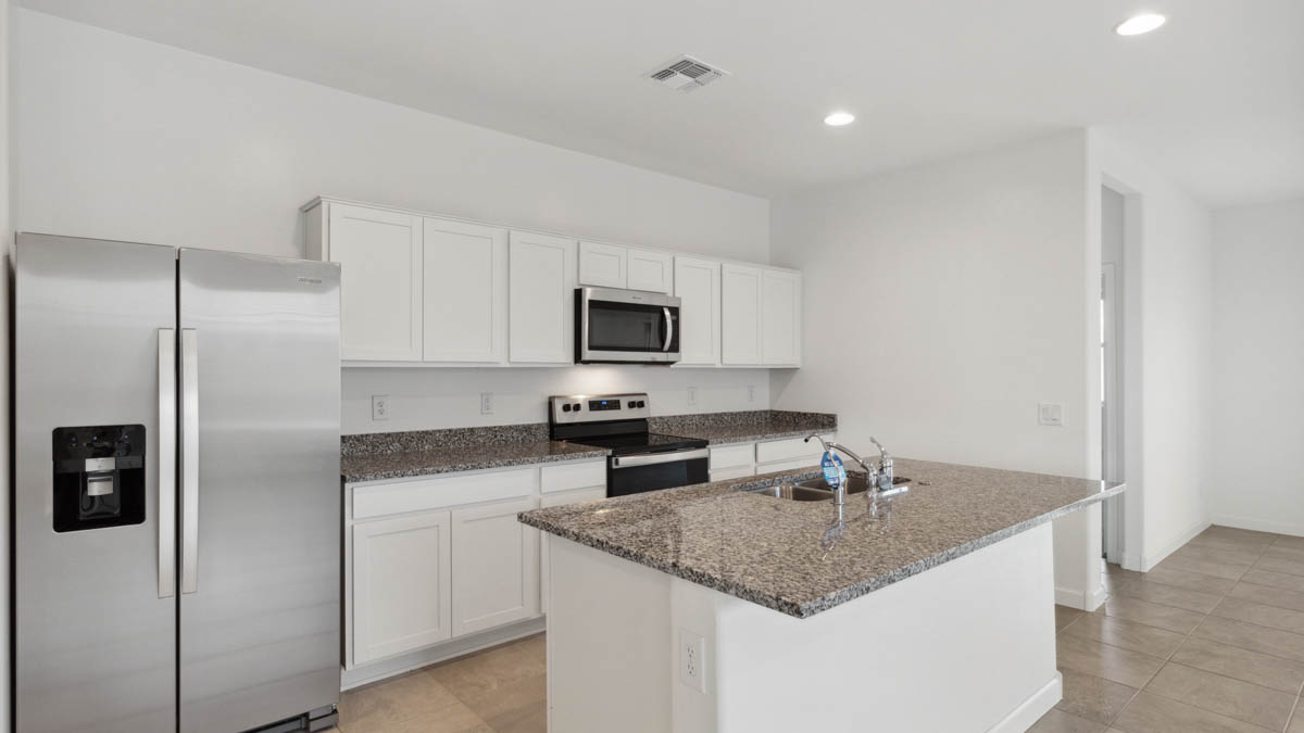 Bright and spacious kitchen with granite countertops, stainless steel appliances, and an island with bar seating.