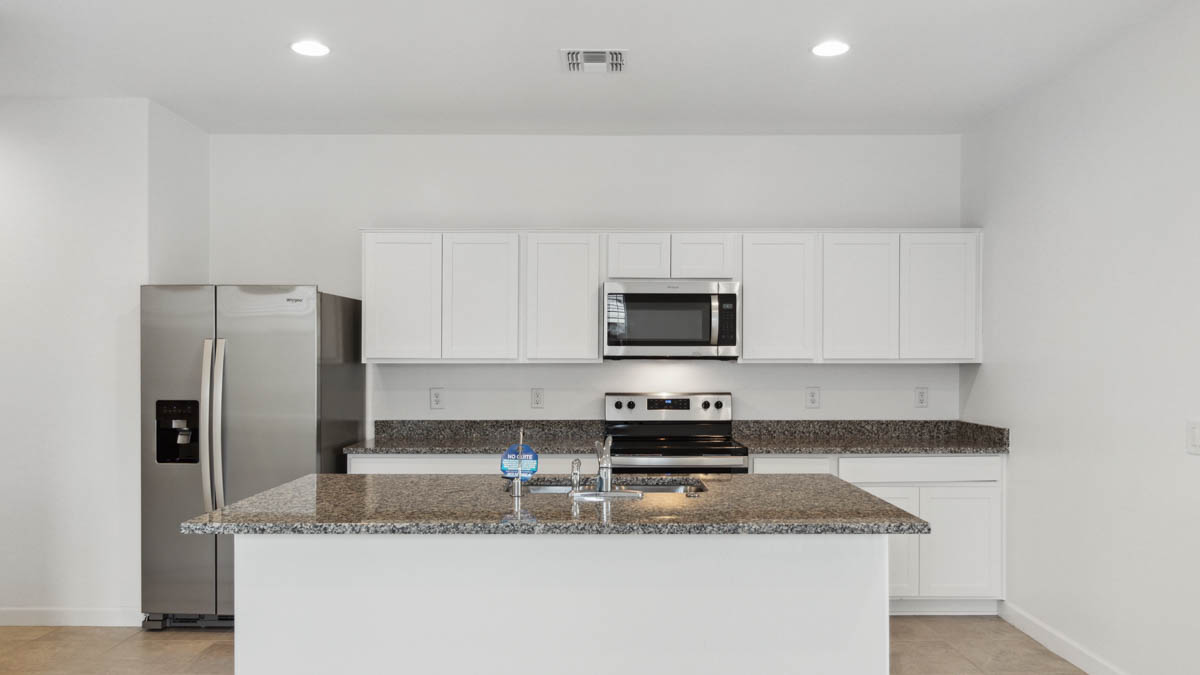 Bright and spacious kitchen with granite countertops, stainless steel appliances, and an island with bar seating.