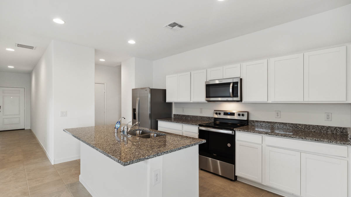 Bright and spacious kitchen with granite countertops, stainless steel appliances, and an island with bar seating.