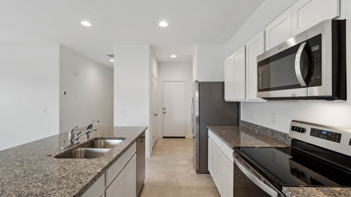 Bright and spacious kitchen with granite countertops, stainless steel appliances, and an island with bar seating.