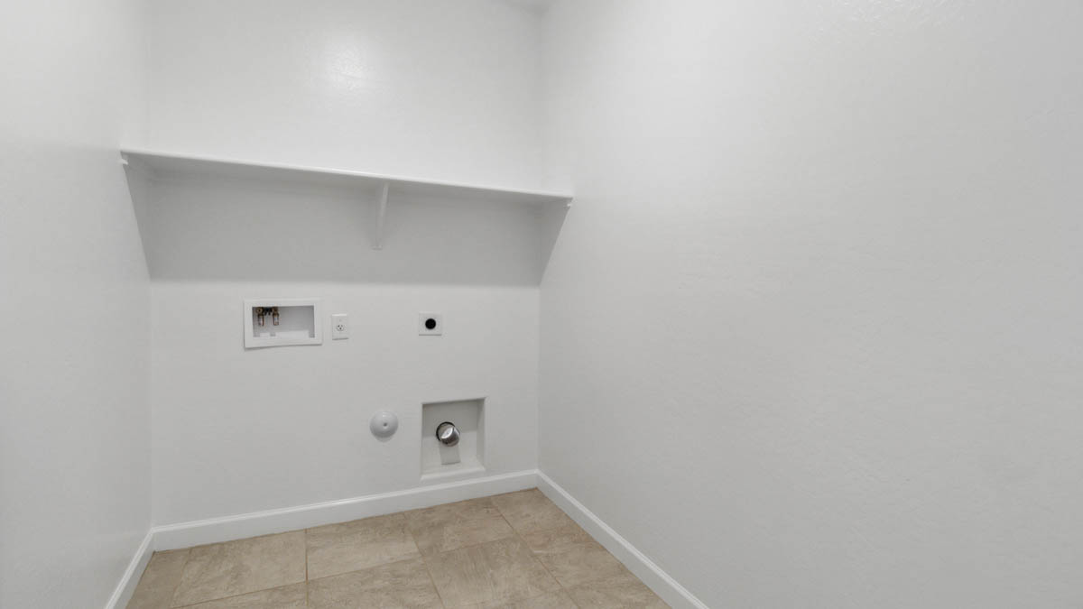 Spacious laundry room with washer and dryer connections and shelving for storage.